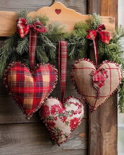Three fabric heart ornaments hanging from pine greenery on a rustic wooden wall