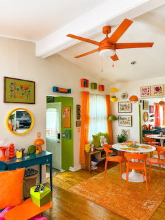 Colorful retro living room with orange furniture, ceiling fan, and eclectic wall art
