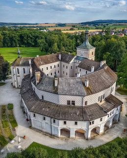 Aerial view of a historic Czech chateau with round courtyard, tower, and green countryside