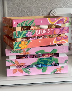 Stack of pink and colorful hand-painted wooden crates with tropical flower and sea turtle designs