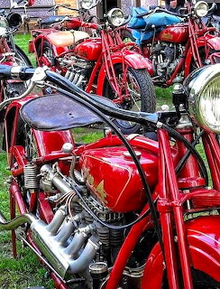 Row of red vintage Indian motorcycles parked on grass at an outdoor show