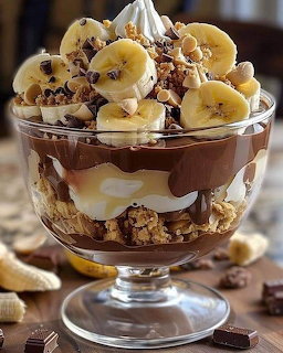 Layered chocolate banana trifle dessert in clear glass bowl with whipped cream and cookie crumbles on top