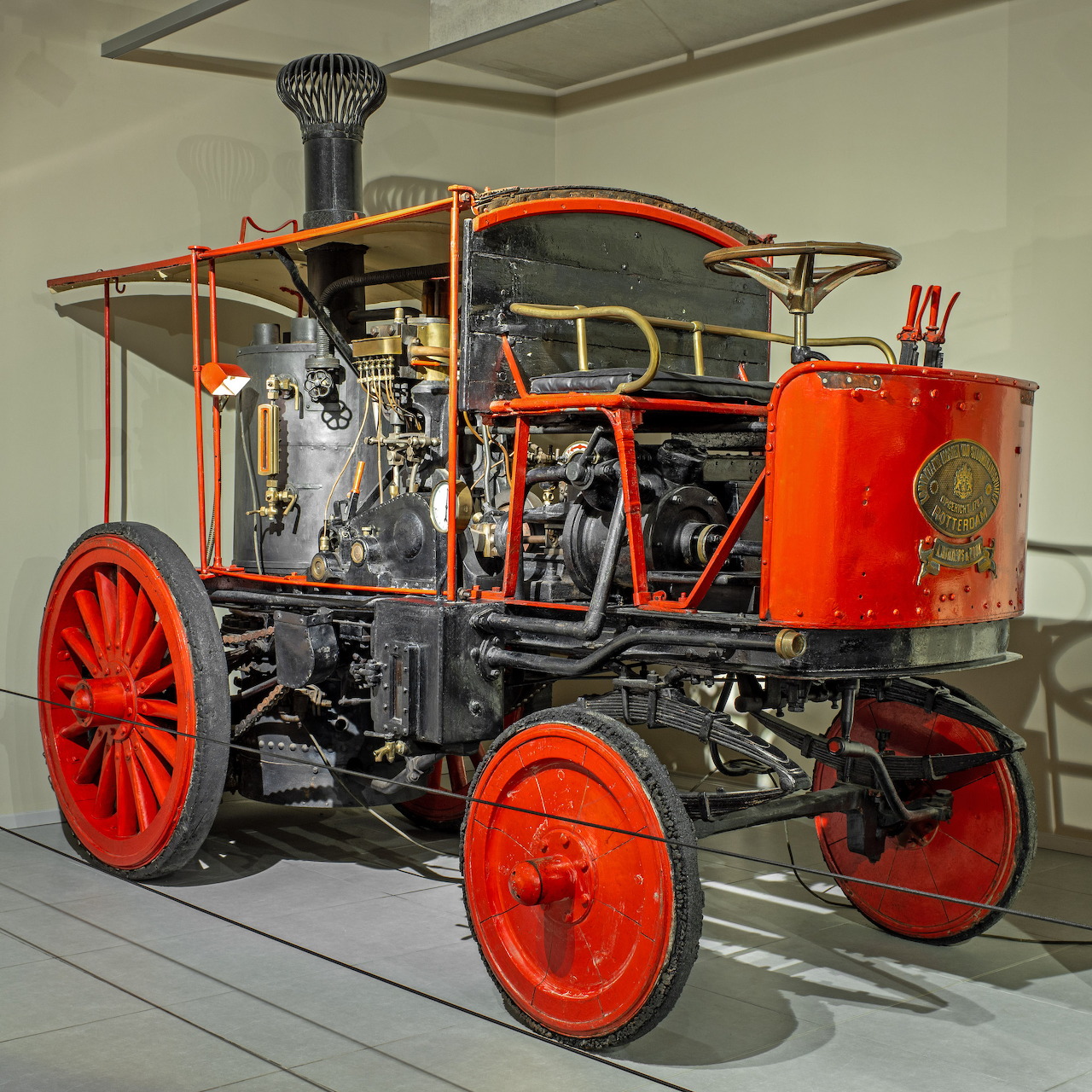 Vintage 1907 Bikkers steam sanitation vehicle with red wheels on display indoors