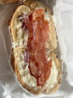 Open bagel with cream cheese and smoked salmon on white paper