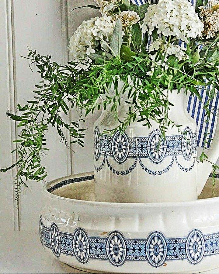 White flowers in a blue and white ceramic pitcher inside a matching basin