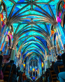 Gothic cathedral interior with vibrant blue illuminated vaulted ceiling and stained glass windows