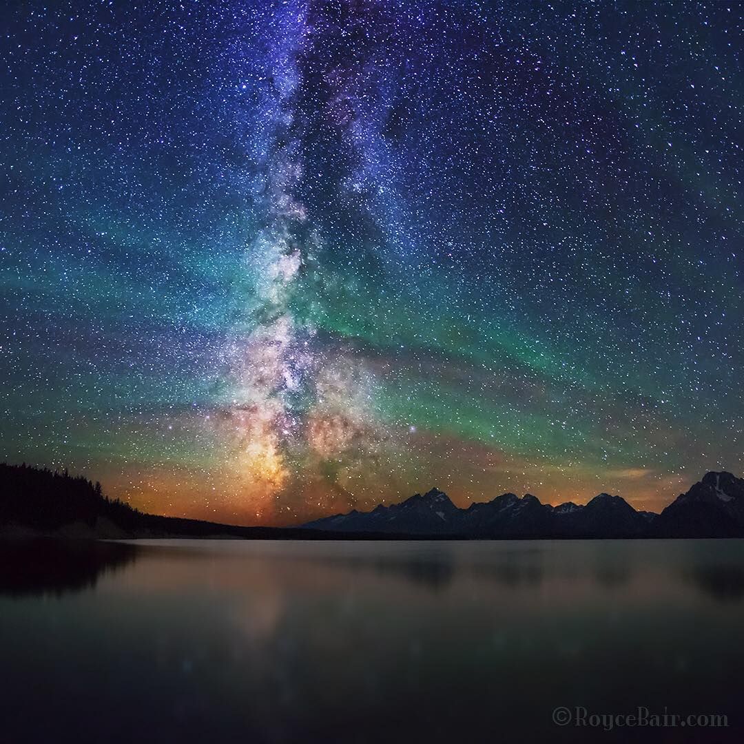 Milky Way galaxy stretching vertically over a tranquil mountain lake at night with star-filled sky