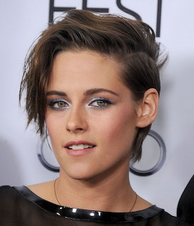 Close-up portrait of Kristen Stewart with short tousled hair and smoky eye makeup.
