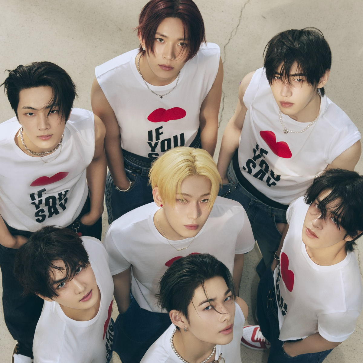 Seven young men in white sleeveless shirts posing together and looking up at the camera