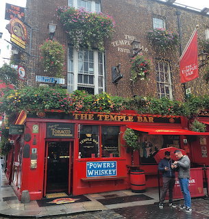 Red Temple Bar pub with hanging flower baskets and ivy-covered brick building, people outside