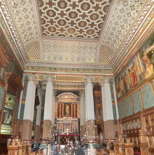 Ornate chapel interior with decorated ceiling, marble columns, and golden altar at Castle Howard