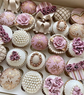 Pastel pink and white cupcakes with fondant roses, pearls and gold details in a box