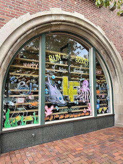 Arched bookstore window with shelves of books and colorful posters on brick building