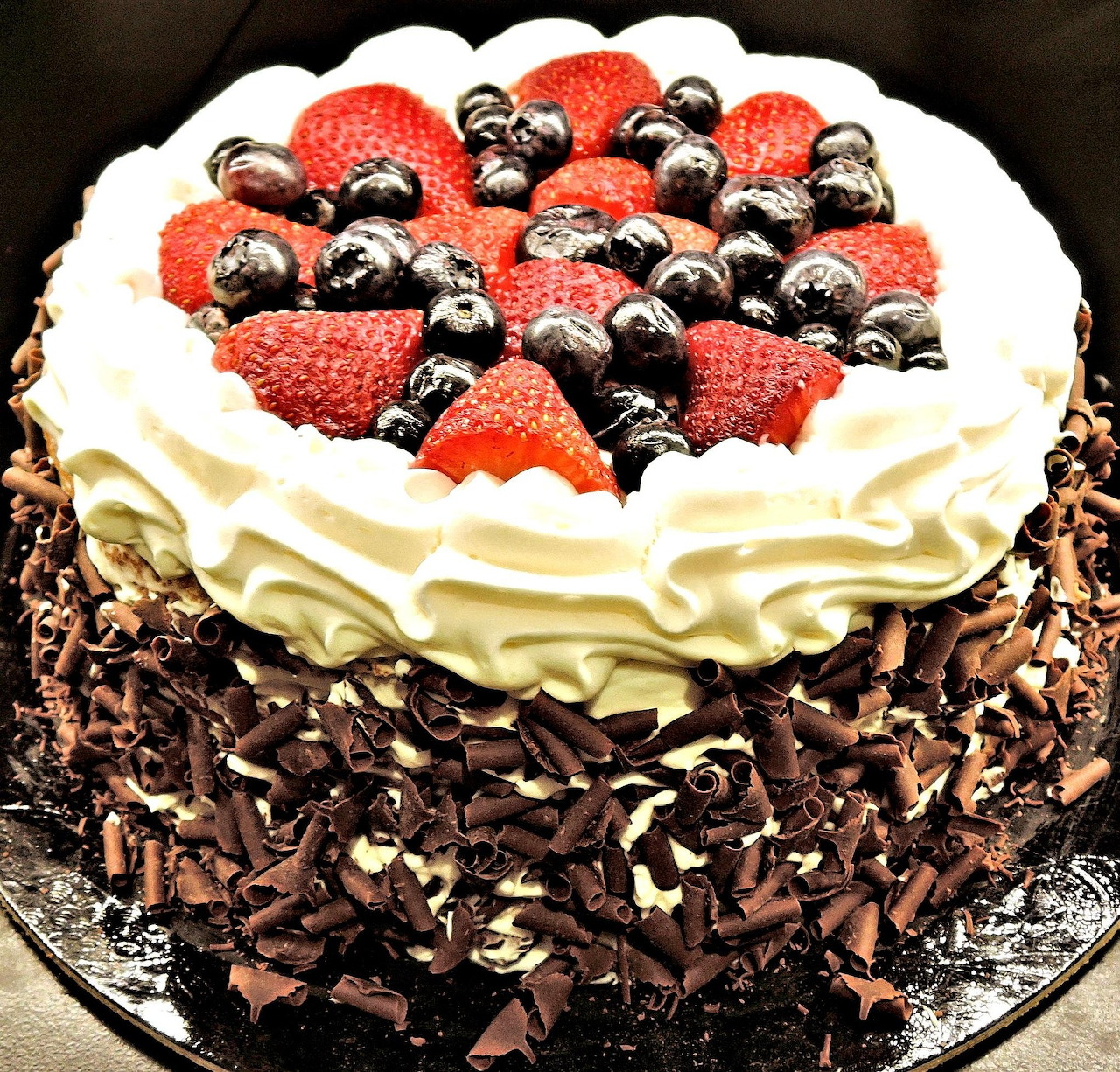 Chocolate layer cake topped with strawberries, blueberries, and whipped cream