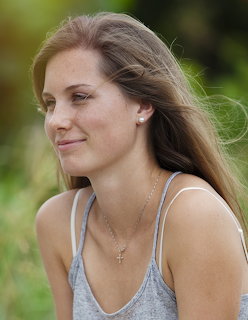 Side profile portrait of woman with long brown hair outdoors in natural light