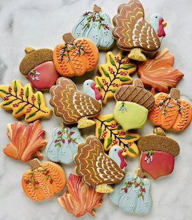 Decorated Thanksgiving sugar cookies shaped as turkeys, pumpkins, leaves, and acorns with colorful icing