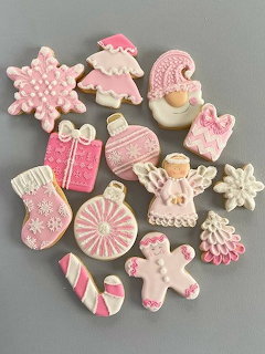 Assorted pink and white decorated Christmas cookies including gingerbread men, snowflakes, and holiday shapes