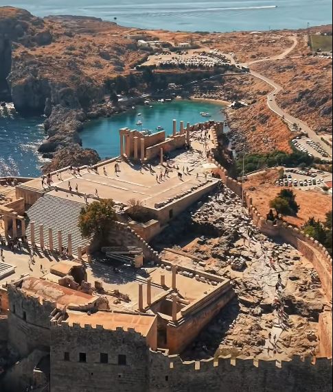 Aerial view of Lindos Acropolis on Rhodes, Greece, showing ancient ruins, walls, and a blue bay