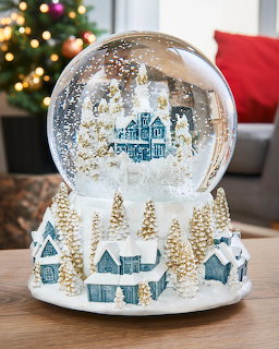 Christmas snow globe with miniature village and trees on wooden table