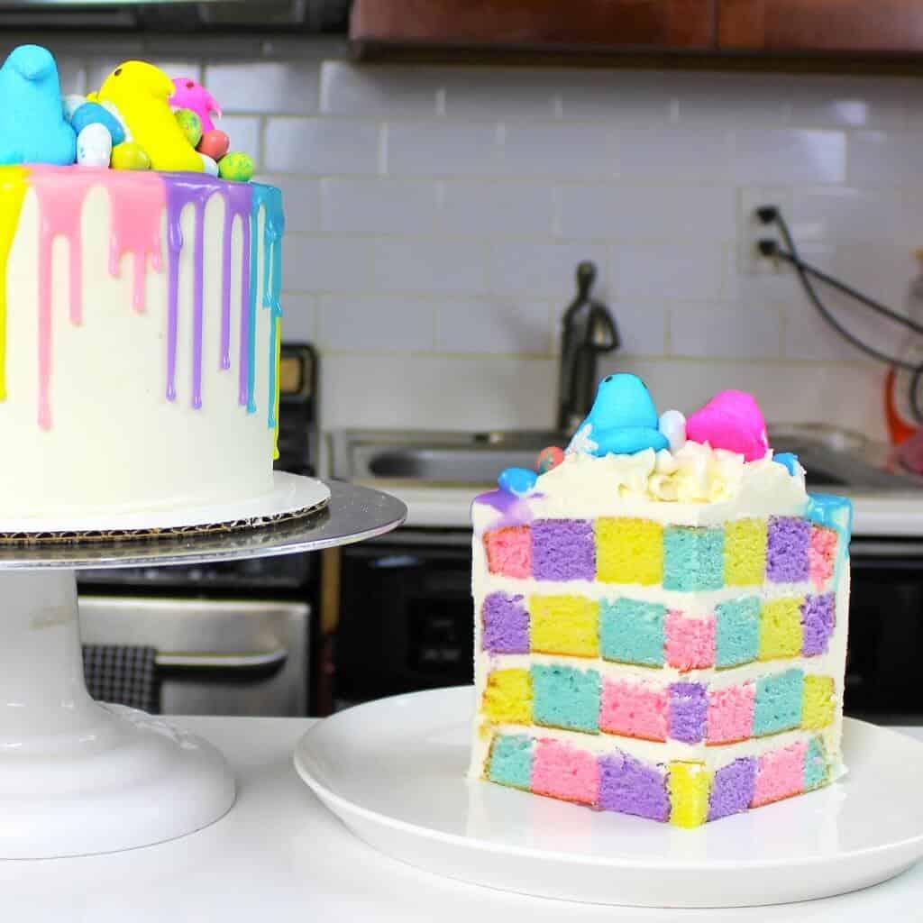 Two colorful decorated cakes on white cake stands in a modern kitchen setting
