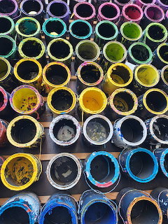 Overhead view of colorful paint cans arranged in rows showing various paint colors