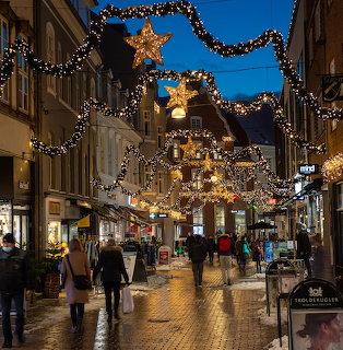 Illuminated Christmas street decorations at dusk in Viborg, Denmark with pedestrians walking on cobblestone street