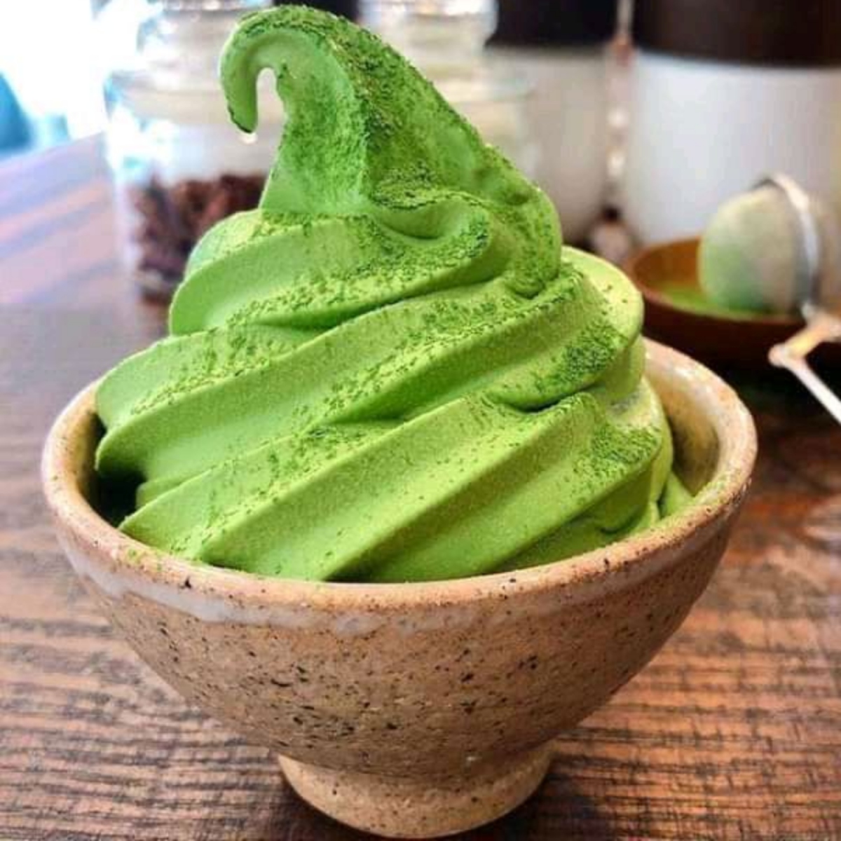 Green matcha soft serve ice cream in a ceramic bowl on a wooden table