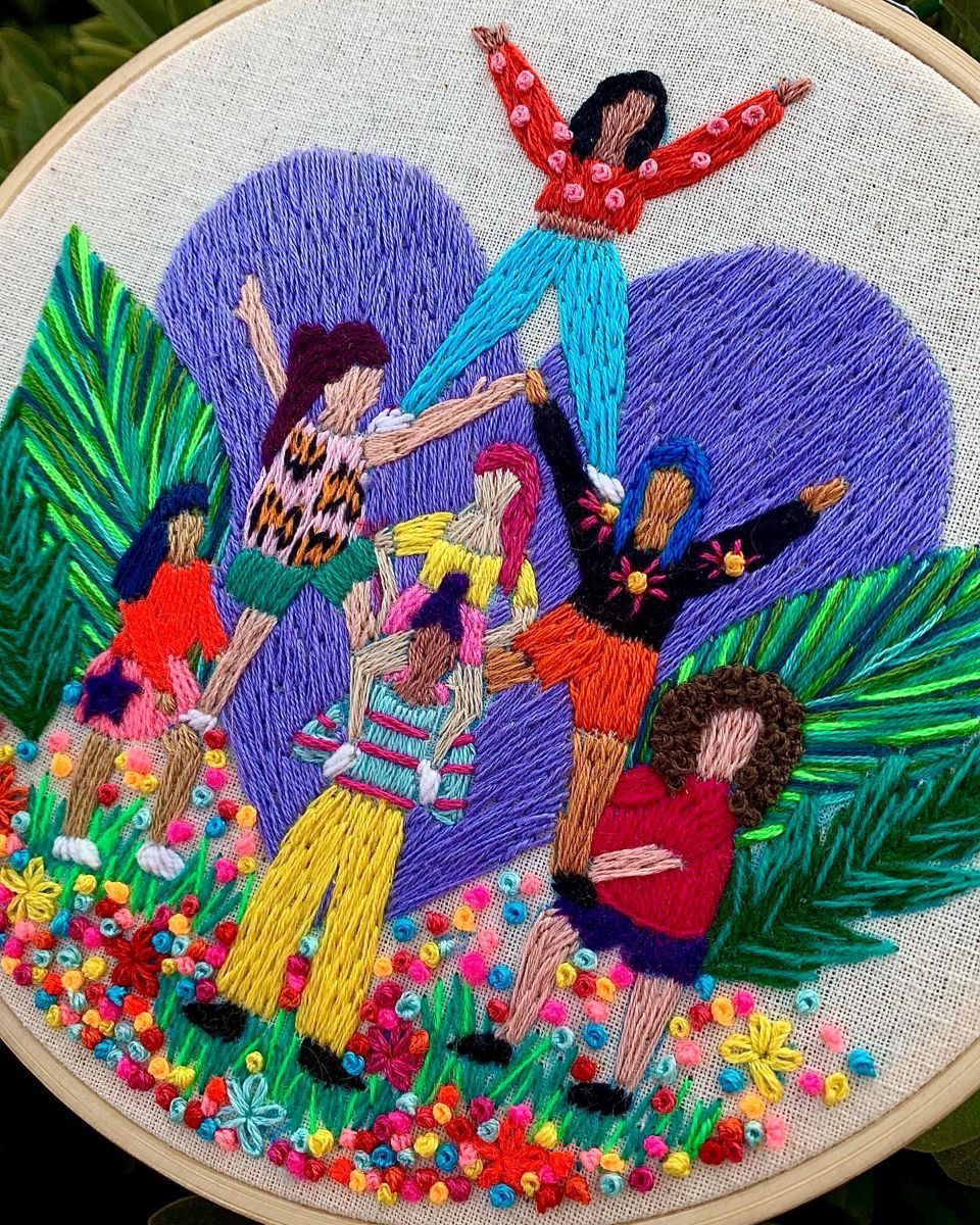 Embroidery hoop art showing women dancing together with tropical leaves and colorful flowers