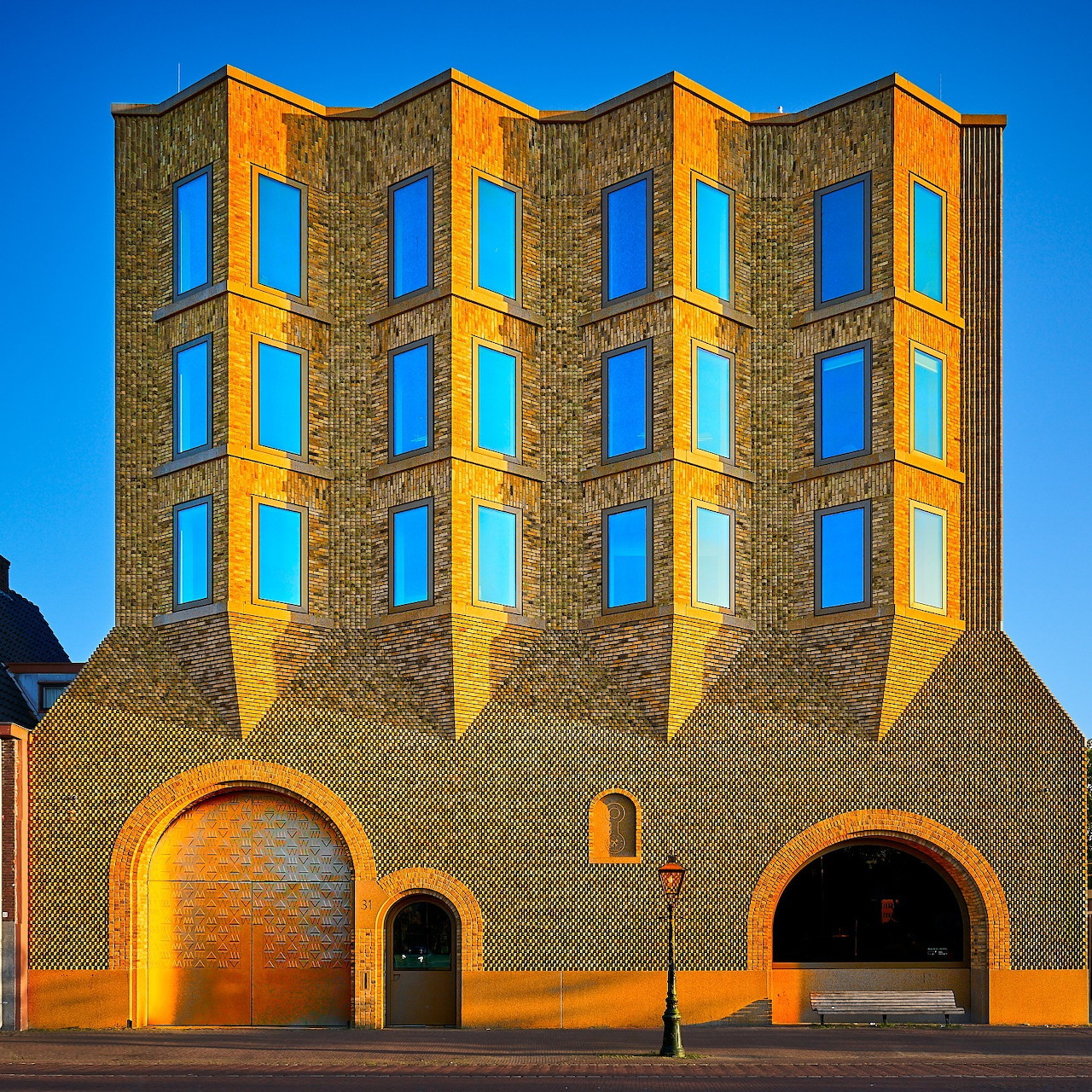 Historic building facade with five arched sections featuring blue windows and yellow-orange brick walls against clear sky