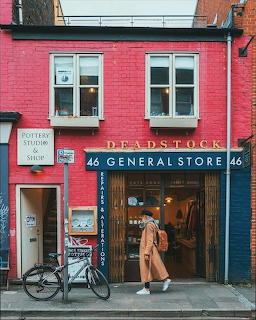 Pink building with Deadstock General Store signage, bicycle parked by entrance, person in doorway