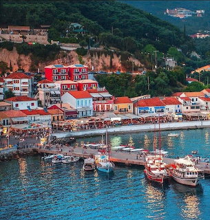 Colorful harbor in Parga, Greece with waterfront buildings, boats, and green hillside