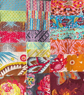 Colorful patchwork quilt with diverse fabric patterns in squares including florals, geometrics, and ornamental designs