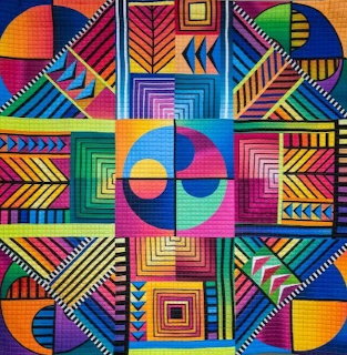 Colorful geometric quilt with triangles, chevrons, circles and squares in bright rainbow hues