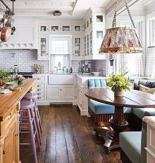 Bright white cottage kitchen with wooden island and cozy breakfast nook with blue cushions