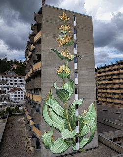 Floral mural on the side wall of a tall apartment building with cloudy sky overhead