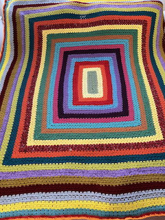 Handmade crochet blanket with concentric rectangular stripes in many bright colors