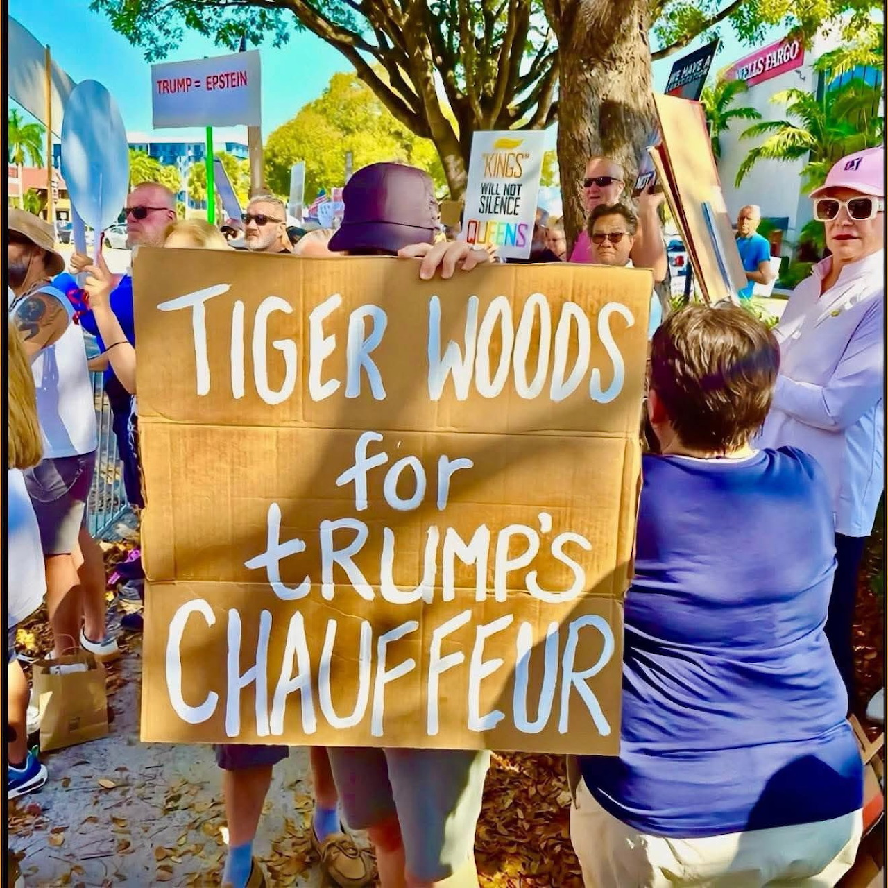 Handmade protest sign held by people at an outdoor street demonstration