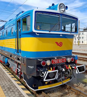 Blue and yellow electric locomotive 750 022-3 on platform with overhead wires