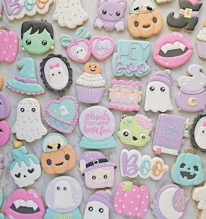 Assortment of pastel-colored decorated Halloween cookies with cute ghosts, pumpkins, bats, and monsters
