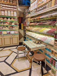 Traditional candy shop interior with shelves of colorful sweets and a small table with stools