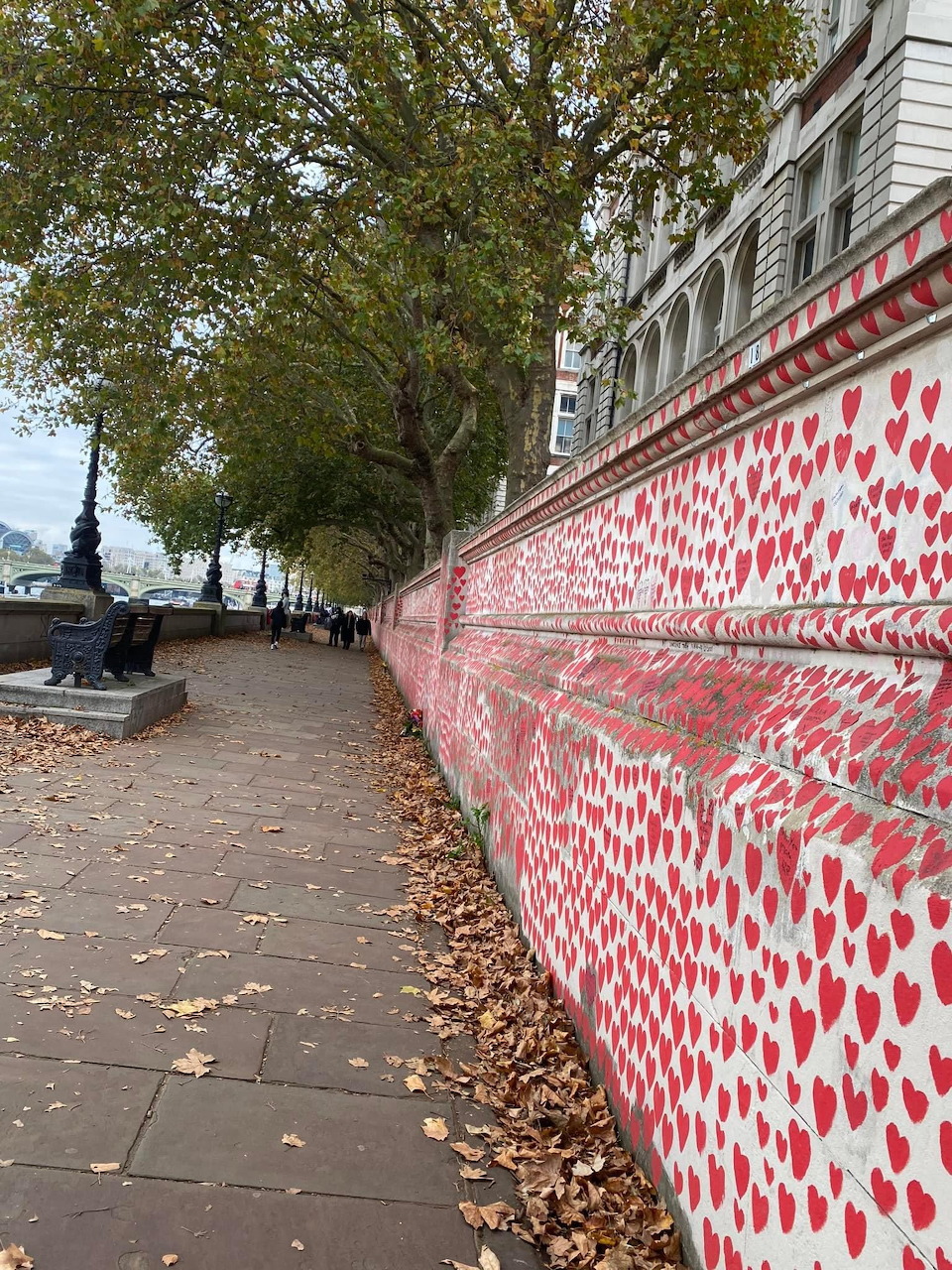 Long riverside wall covered in thousands of hand-painted red hearts forming the National Covid Memorial Wall in London.