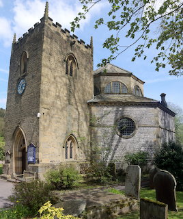 Stone church with square tower and round apse in a churchyard with gravestones and trees