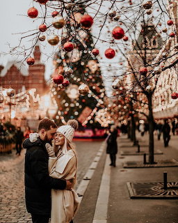 Couple embracing at illuminated Christmas market with ornaments and decorated trees