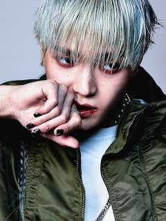 Close-up portrait of a young man with silver hair, dark eye makeup, and a green jacket