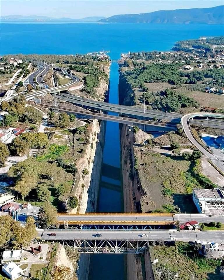 Aerial view of the Corinth Canal with bridges, road interchanges, and blue sea in the background