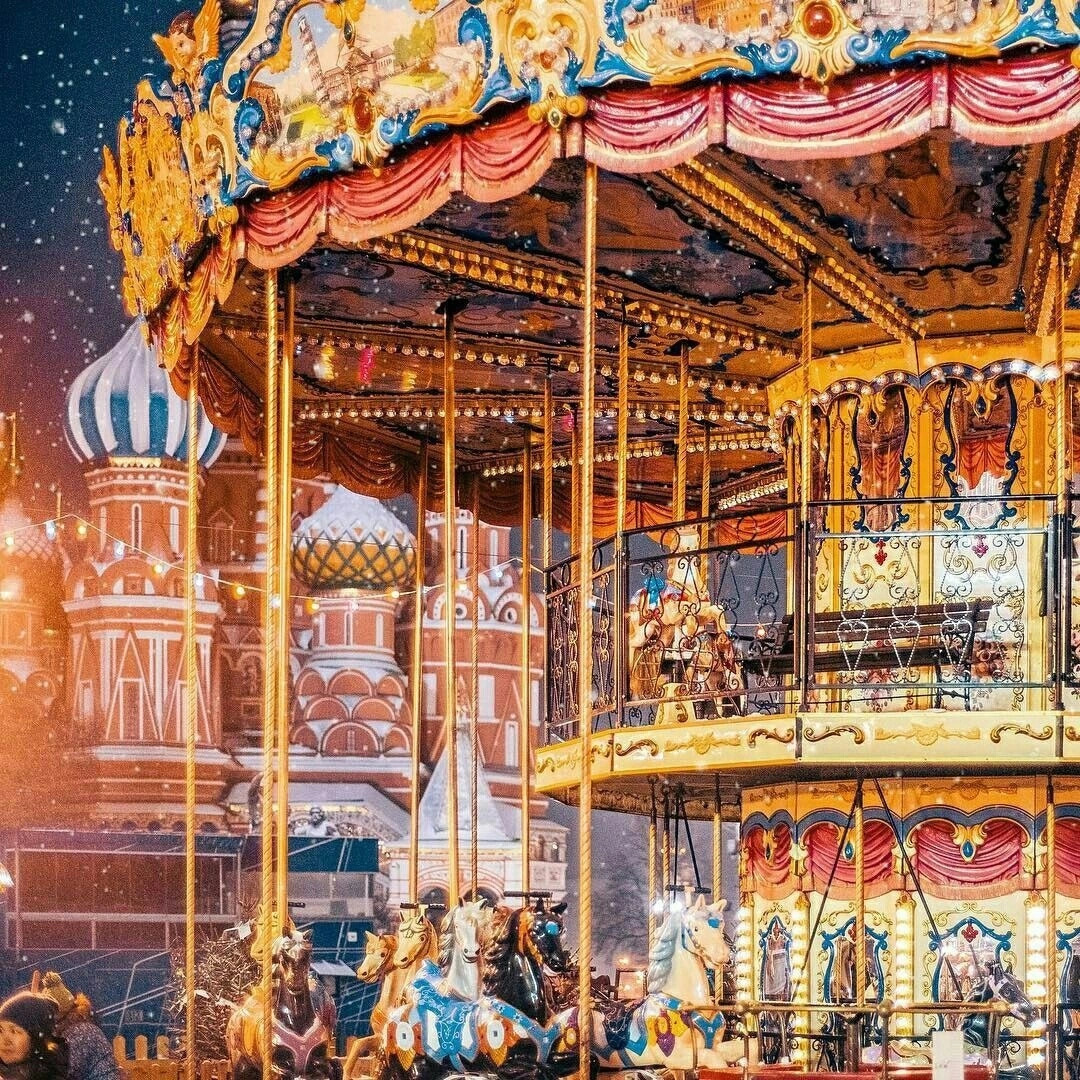 Colorful night painting of an illuminated carousel with ornate buildings behind it