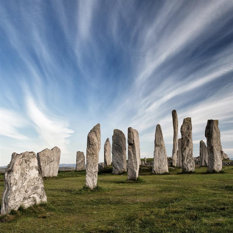 Calanais standing stones in a circle on grass under streaked blue sky
