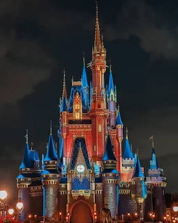 Illuminated Disney-style castle with blue turrets and spires at night