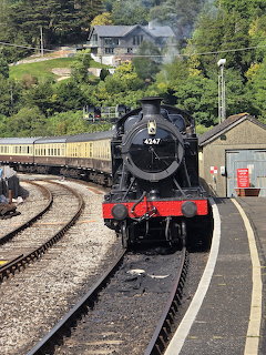 Black steam train with red details arriving at Kingswear railway station on curved tracks