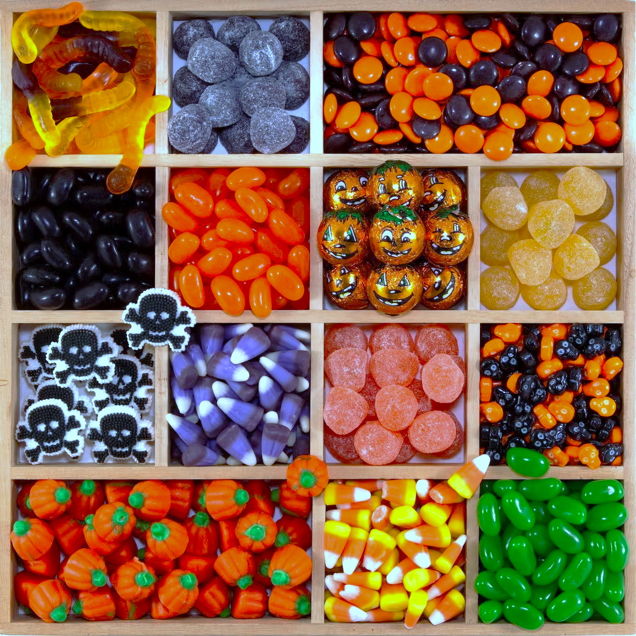 Grid display of assorted Halloween candies in various colors and shapes including skulls, pumpkins, and seasonal treats